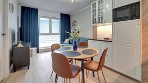 Eine moderne Küche mit weißen Schränken, einer schwarzen Mikrowelle und einem Essbereich mit einem runden Tisch und Stühlen.