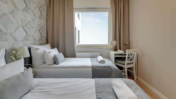 Ein Hotelzimmer mit zwei Betten, einem Fenster, einem Schreibtisch und einem Stuhl.