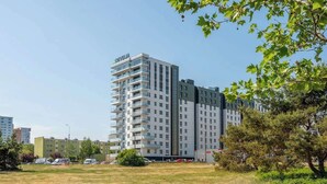 Ein mehrstöckiges Hotel im modernen Stil, mit Balkonen auf jeder Etage, einer flachen Dachkonstruktion und umgeben von einer Grünfläche mit Bäumen.