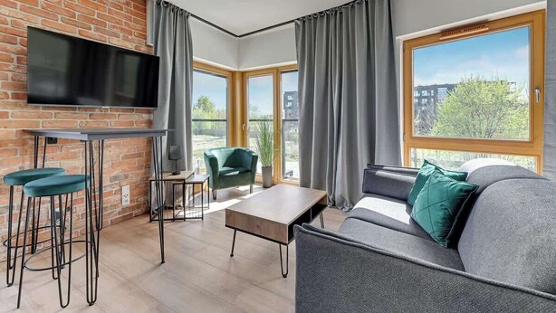 Ein modernes Wohnzimmer mit Backsteinwand, Flachbildfernseher, Sofa, Couchtisch und einer Bar mit Hockern.