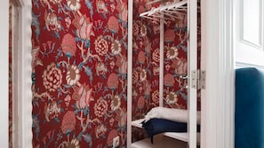 A room with a patterned red wall, a white wardrobe, and a blue bed. - Mouzinho 120 | Stylish Studio by LovelyStay (Porto)