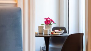 A dining table with a white coffee cup, a white mug, a white bowl with fruit, and a white vase with pink flowers. - Mouzinho 120 | Stylish Studio by LovelyStay (Porto)