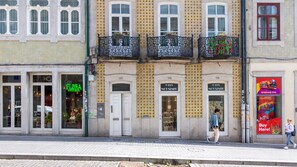 A street view with a building featuring a shop named 'Casa Mousinho' and a storefront with a neon sign 'Flora'. - Mouzinho 120 | Stylish Studio by LovelyStay (Porto)