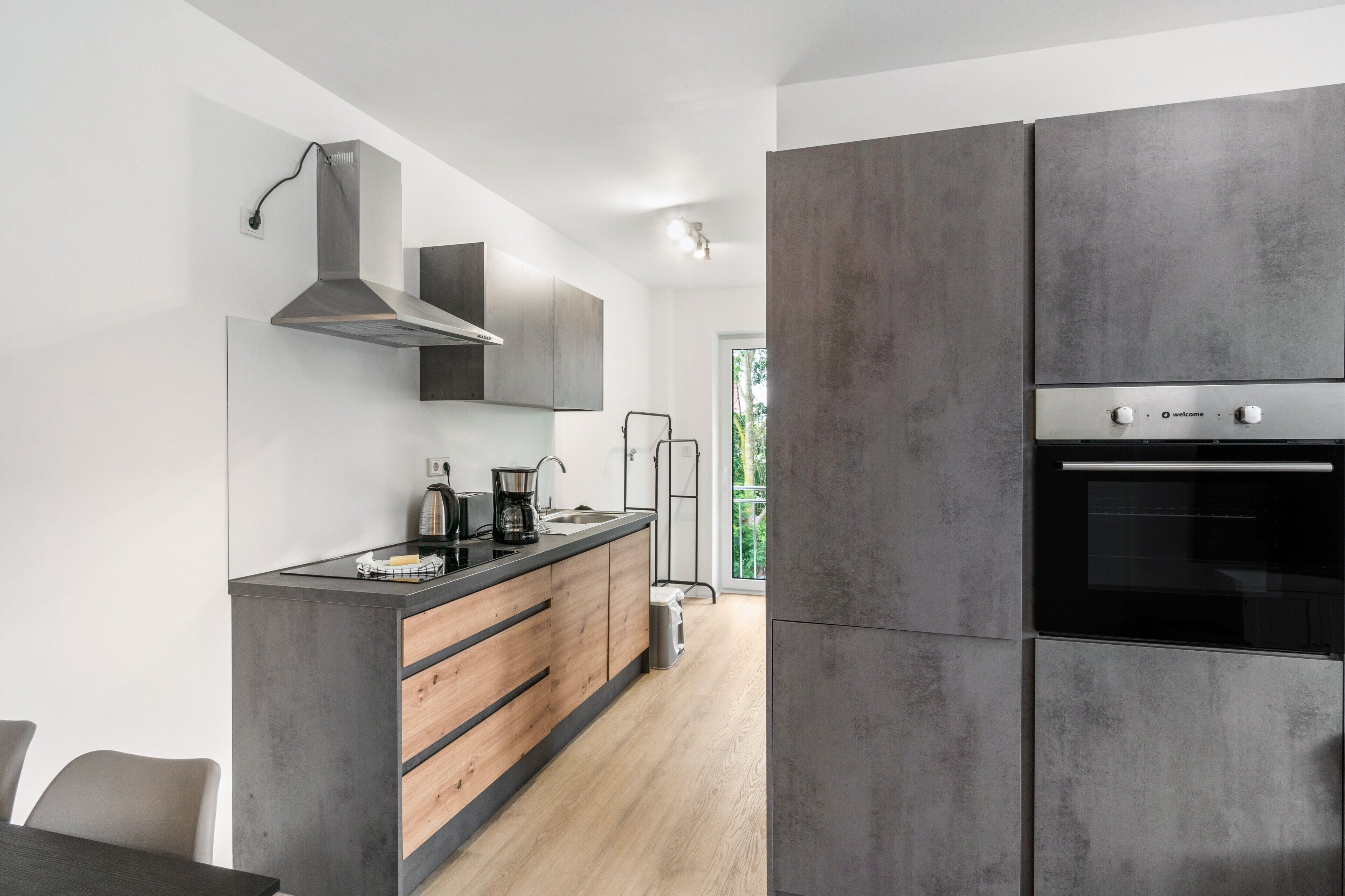 A modern kitchen with a built-in oven, a coffee maker, and a stainless steel range hood.
