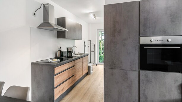Una cucina moderna con forno integrato, macchina da caffè e cappa aspirante in acciaio inossidabile.