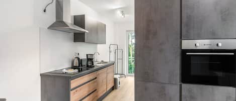 A modern kitchen with a built-in oven, a coffee maker, and a stainless steel range hood.