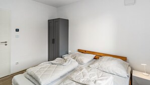 Una camera da letto con un letto, un armadio, un comodino e una lampada a parete.