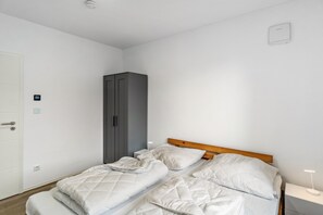 Ein Schlafzimmer mit einem Bett, einem Kleiderschrank, einem Nachttisch und einer Wandleuchte.