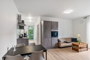 A modern kitchen with a built-in oven and a dining area with a table and chairs. - Apartment 'Haus Seeluft – W6' with Wi-Fi (Butjadingen)