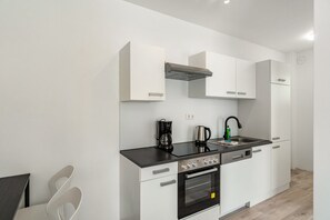 Eine moderne Küche mit weißen Schränken, einer schwarzen Arbeitsplatte, einem eingebauten Ofen und einer Kaffeemaschine.