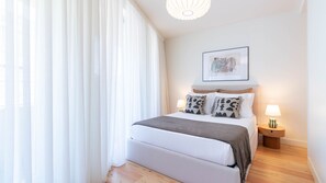 A bedroom with a bed, bedside tables, a lamp, and a framed picture on the wall. - Cozy Porto Home w/ AC by LovelyStay (Porto)
