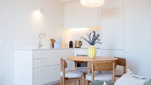 Una cocina moderna con armarios blancos, una mesa redonda de madera y dos sillas.