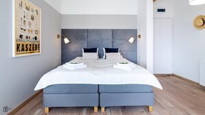 Une chambre moderne avec un grand lit, deux lampes de chevet et une affiche accrochée au mur.