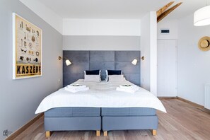 Ein modernes Schlafzimmer mit einem großen Bett, zwei Nachttischlampen und einem Poster an der Wand.