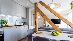 Une cuisine moderne avec des meubles blancs, une table à manger avec des chaises et un escalier en bois.