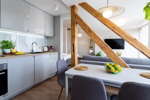Eine moderne Küche mit weißen Schränken, einem Esstisch mit Stühlen und einer Holztreppe.