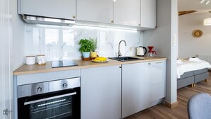 Une cuisine moderne équipée d’un four encastré, d’un évier et d’un plan de travail agrémenté d’une plante en pot et d’une machine à café.