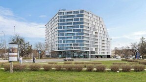 Ein modernes Hotel mit Eckgebäude, mehreren Stockwerken und einer Glasfassade.