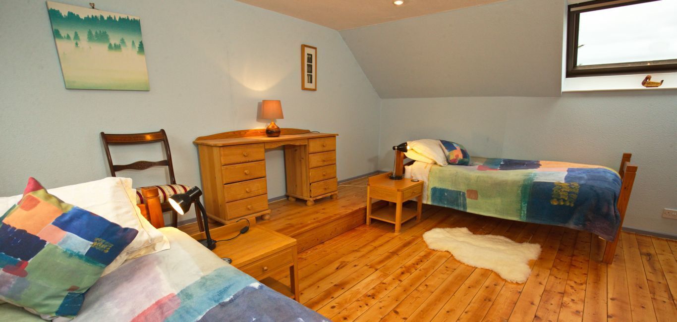 Ein Schlafzimmer mit zwei Betten, einem Schreibtisch, einem Stuhl, einer Lampe und einem Bild an der Wand.