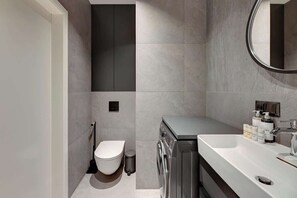 Uma casa de banho moderna com sanita, máquina de lavar roupa e lavatório.