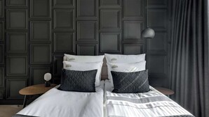 A bed with a quilted cover, two pillows, a bedside table with a lamp, and a dark wall with a geometric pattern. - Scala 220 with Balcony | City Center | Parking (Gdańsk)