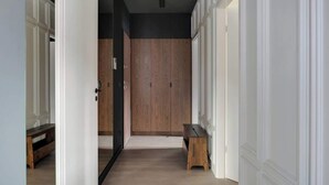 A hallway with a wooden bench, white walls, and a door leading to another room. - Scala 220 with Balcony | City Center | Parking (Gdańsk)