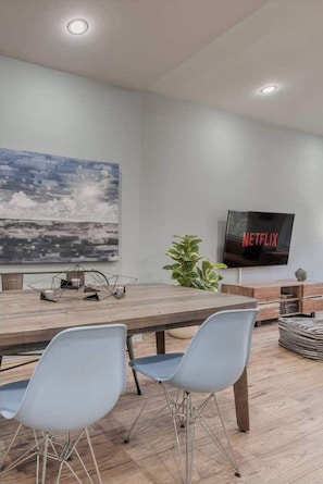 Uma sala de estar moderna com área de jantar, televisão de tela plana e uma grande pintura abstrata.