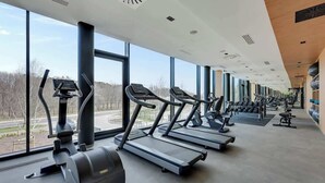 A gym with treadmills, ellipticals, and free weights, large windows, and a modern design. - Tarasy Bałtyku 5 | Seaside | Billard, Sauna & Gym (Gdańsk)