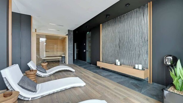 A modern spa area with lounge chairs, a wall-mounted water feature, and a reception desk. - Tarasy Bałtyku 5 | Seaside | Billard, Sauna & Gym (Gdańsk)