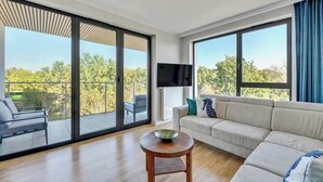 A modern living room with a sofa, a round wooden table, and a TV. - Tarasy Bałtyku 5 | Seaside | Billard, Sauna & Gym (Gdańsk)