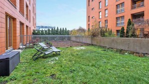 Ein Innenhof mit Rasenfläche, Gartenmöbeln und Blick auf ein rotbacksteins Gebäude mit zahlreichen Fenstern.