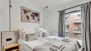 Une chambre d’hôtel avec un lit, une table de chevet, une carte du monde accrochée au mur et une vue sur l’extérieur.