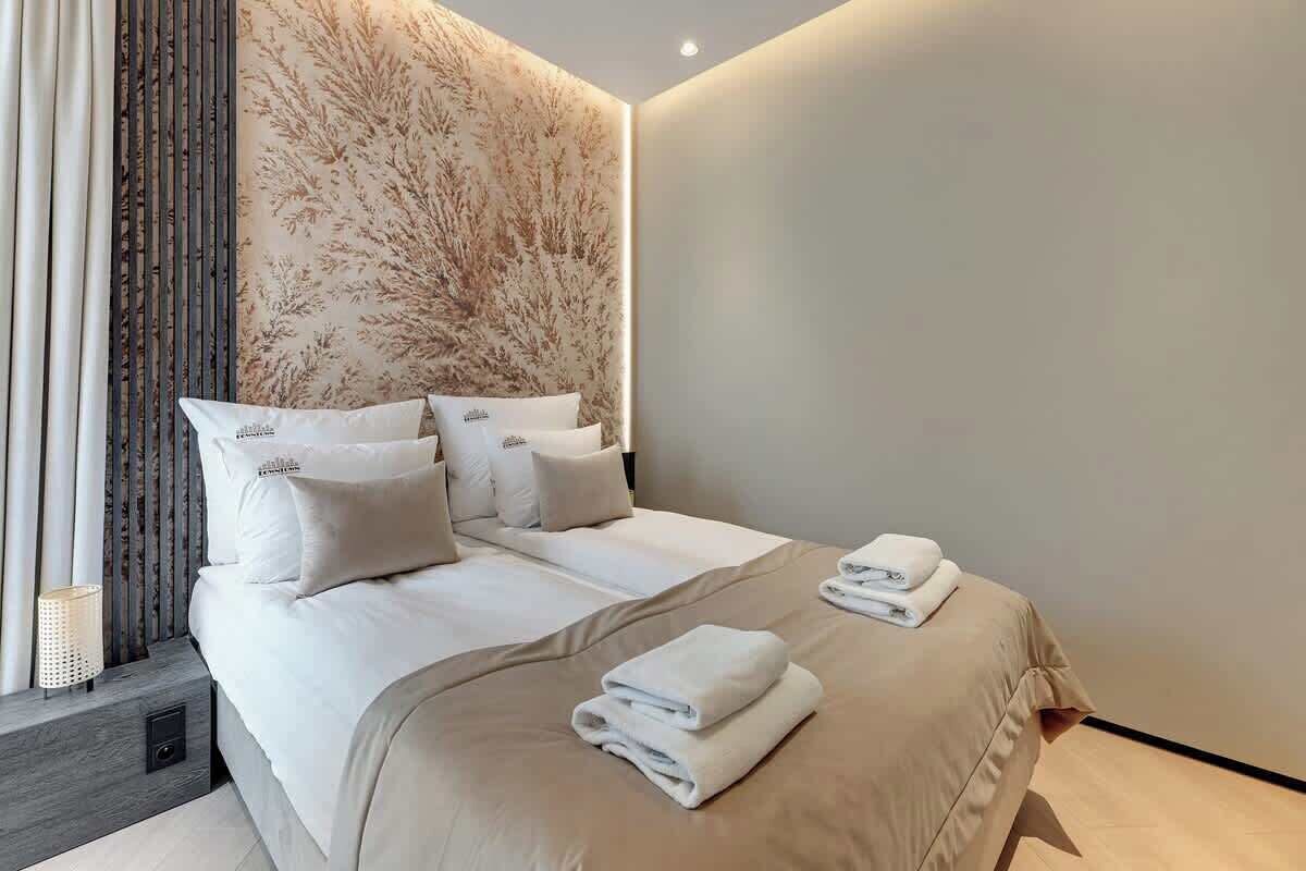 A modern hotel room with a large bed, a decorative wall, and a window with curtains.