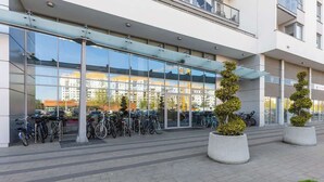 Ein modernes Gebäude mit Glasfassade, einer Reihe von Fahrrädern und Blumentöpfen.