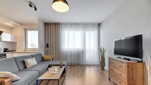 Ein modernes Wohnzimmer mit Sofa, Couchtisch, Fernseher und Holzschrank.