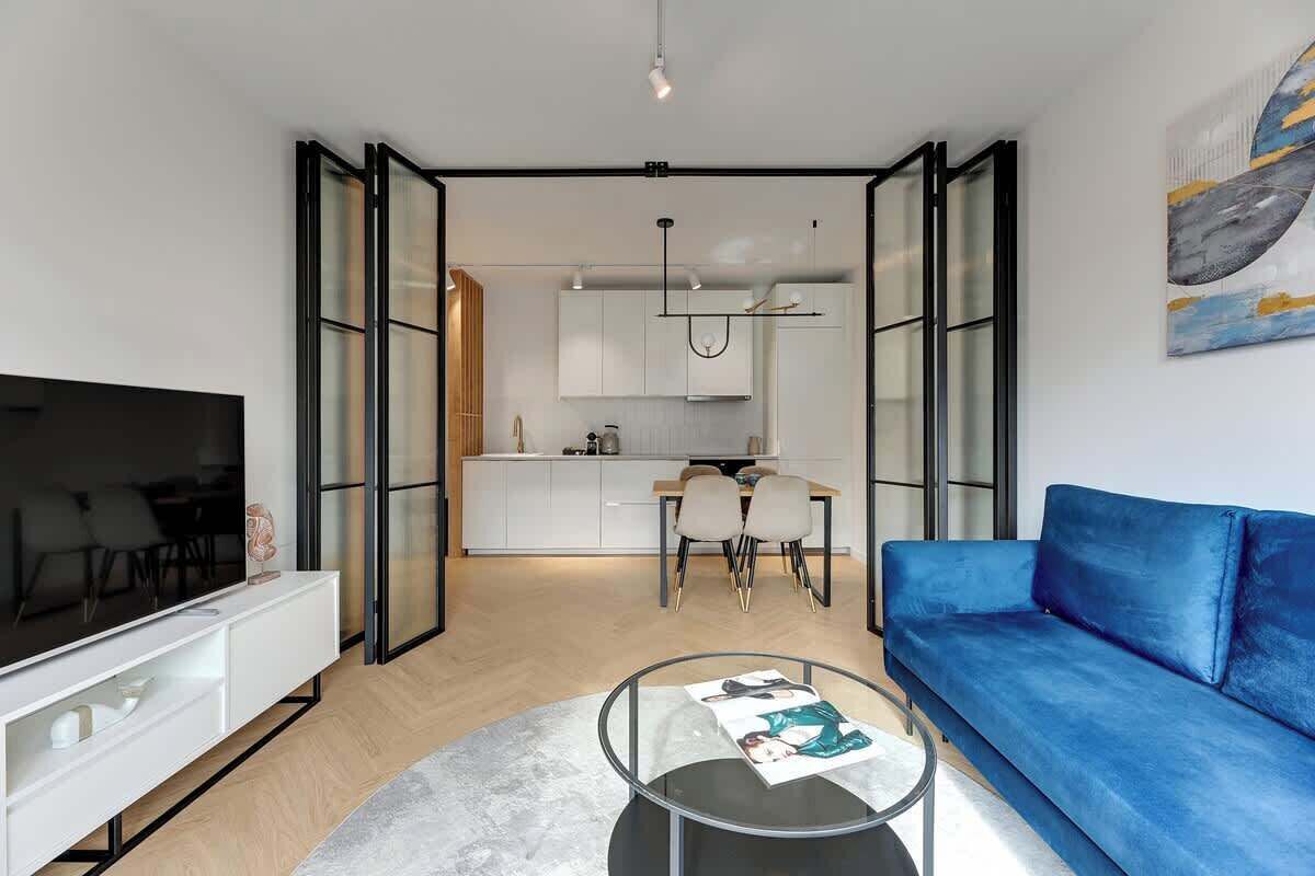 Ein modernes Wohnzimmer mit einem Flachbildfernseher, einem blauen Sofa und einem Glastisch.