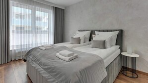 A modern hotel room with a large bed, a bedside table, and a view through sheer curtains. - Bastion Wałowa 10 | City Center | Parking (Gdańsk)