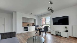 A modern living space with a dining area, kitchen, and a large TV on the wall. - Bastion Wałowa 10 | City Center | Parking (Gdańsk)
