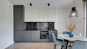 Uma cozinha moderna com armários cinza, lava-louças e um espaço de jantar com mesa e cadeiras.