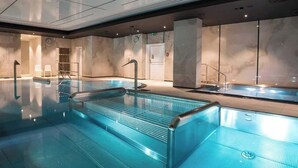 En modern inomhuspool med klart vatten, glasväggar och en minimalistisk design.