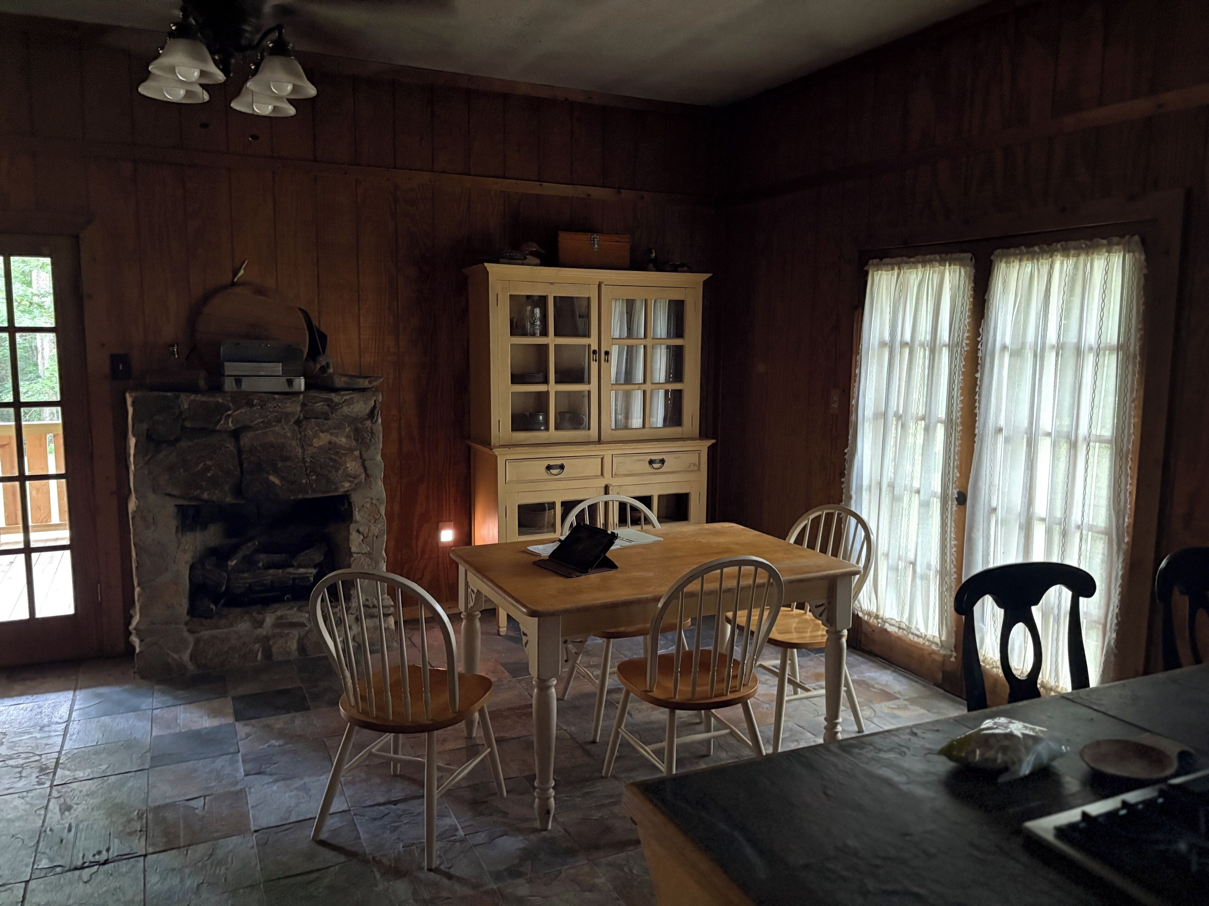 Uma sala de jantar com lareira de pedra, armários de madeira e uma mesa com cadeiras.