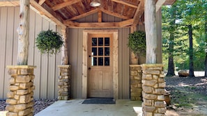 A wooden door with a stone base, flanked by two stone pillars, and a hanging planter above it. - Rustic lake cabin. Perfect for fisherman and nature lovers.  (Prosperity)