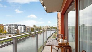 A balcony with a table and chairs, overlooking a river and buildings. - Aura Island 90 Deluxe | River View | Parking (Gdańsk)