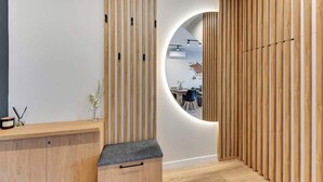 Ein modernes Interieur mit einem Holzerrepsionspult, einem runden Spiegel und einer Wand aus Holzleisten.