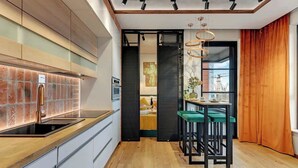 A modern kitchen with a glass backsplash, wooden countertop, and a dining area with bar stools. - Doki C80 | Gdańsk Shipyard & Foodhall (Gdańsk)