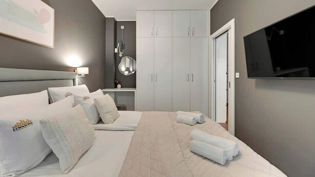 Een hotelkamer met een bed, een televisie, een kledingkast en een spiegel.