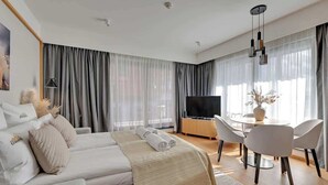 Una habitación de hotel moderna con cama, televisor, escritorio y zona de comedor.