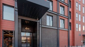 Un bâtiment moderne doté d’un auvent noir, d’une entrée bien visible et d’une façade en briques.