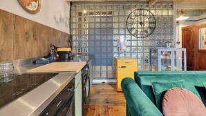 Et køkken med trævæg, et ur, et vintage køleskab og en grøn sofa.