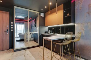 A modern kitchen with a glass door leading to a bathroom, a bar area with stools, and a marble floor. - Nadmotławie291 | Jacuzzi Suite | Riverside & Sauna (Gdańsk)